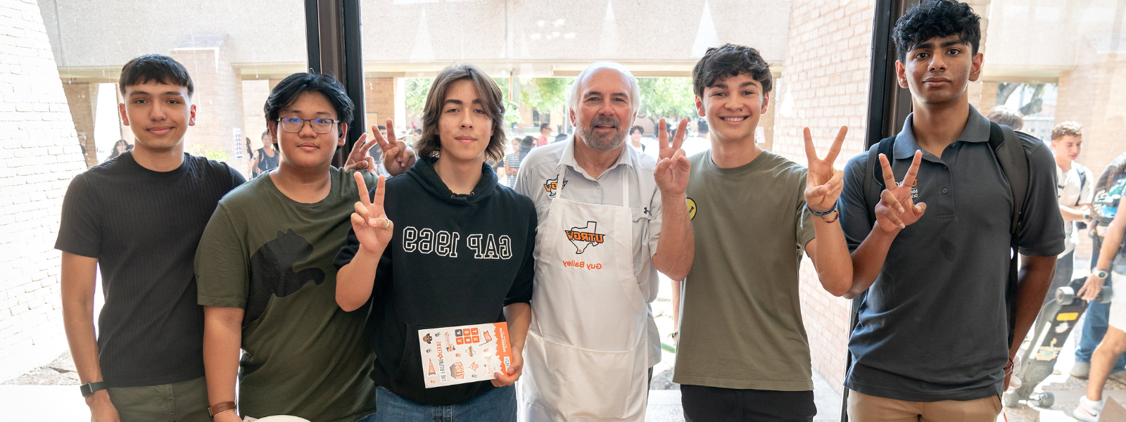  President Bailey and students pose next to him signaling V’s up. 